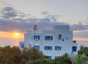 a white building with the sunset in the background at 崖上民宿 Cliff House B&B in Fengbin