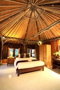 a bedroom with a bed in a room with a roof at Umah Nik Kepitu in Gianyar