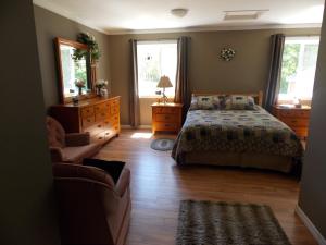 a bedroom with a bed and a couch and two windows at Bear & Butterfly Bed and Breakfast in Gravenhurst