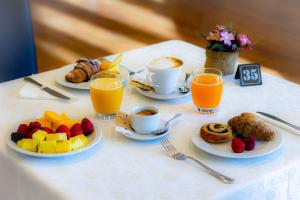 a table topped with plates of fruit and cups of coffee at Tuscany Inn in Montecatini Terme