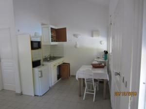 a small kitchen with a table and a white refrigerator at BALAGA ocarina in Sainte-Anne