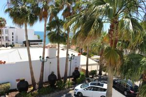 アルブフェイラにあるPassport Algarve Apartmentsのヤシの木が茂る建物の前に停まった白い車