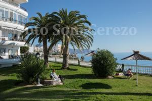 a group of people sitting in the grass near a hotel at Acapulco playa Nerja 407 planta superior in Nerja
