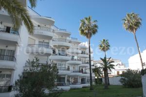 a white building with palm trees in front of it at Acapulco playa Nerja 407 planta superior in Nerja