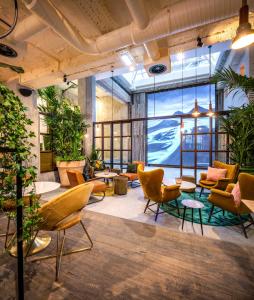 un hall avec des chaises, des tables et des plantes dans l'établissement Hotel Indigo Brussels - City, an IHG Hotel, à Bruxelles