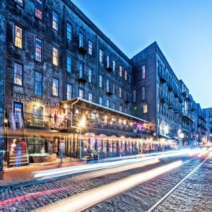 una via cittadina di notte con edifici e binari di River Street Inn a Savannah