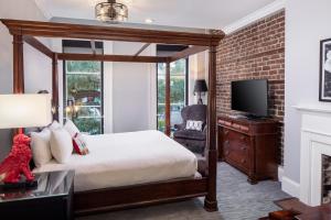 a bedroom with a canopy bed and a tv at River Street Inn in Savannah