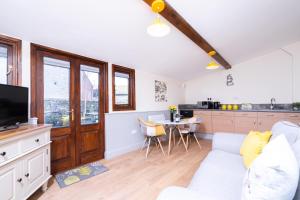 a living room with a white couch and a kitchen at The Brewery lodge in Cirencester