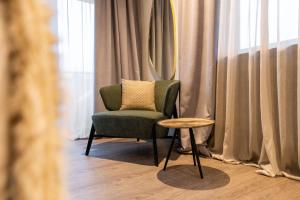 une chaise et une table dans une chambre avec rideaux dans l'établissement Burgus - Design Suites & Apartments, à Burgusio