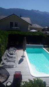 a swimming pool with chairs and an umbrella at fleur de neige in Gilly-sur-Isère