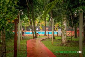 un camino rojo frente a una piscina con árboles en Hotel Don Horacio en Puerto Iguazú
