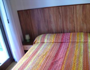 1 dormitorio con 1 cama con cabecero de madera y ventana en Villa Berta, en Riva del Garda