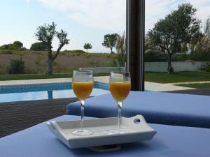 two glasses of wine sitting on a table next to a pool at Villa Oasis Azul - beautiful villa with heated private pool short walk to all amenities in Sesimbra