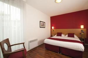 a bedroom with a large bed and a red wall at Séjours & Affaires Lyon Park Lane in Lyon