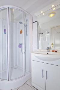 ein weißes Bad mit einer Dusche und einem Waschbecken in der Unterkunft Séjours & Affaires Lyon Park Lane in Lyon