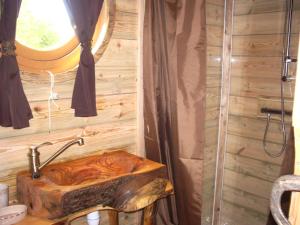 uma casa de banho com um lavatório de madeira e um chuveiro em Roulottes des Trolls em La Boussac