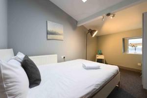 a bedroom with a bed with white sheets and a window at Back Turner Townhouse in Manchester