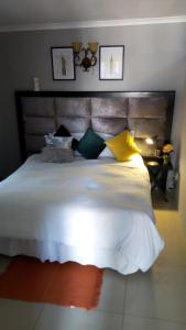- une chambre dotée d'un grand lit avec des oreillers jaunes et verts dans l'établissement Bruno Comfort Suites, à Johannesbourg