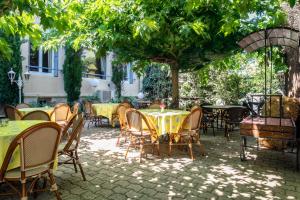 eine Terrasse mit Tischen und Stühlen unter einem Baum in der Unterkunft Hôtel Mireille in Arles