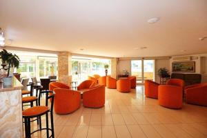 een lobby met oranje stoelen en tafels in een restaurant bij Hotel Bamar in Cervia