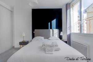 Un dormitorio con una cama blanca con toallas. en Comfy 1 bedroom close to the station - Dodo et Tartine en Toulon