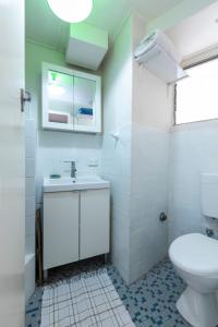 a white bathroom with a toilet and a sink at Sunlit Studio in The Trees, Walk to The Beach in Sydney