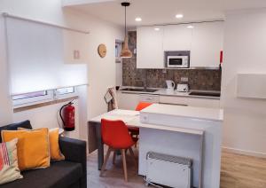 a kitchen and living room with a table and a couch at Casas da Avó II in Santa Cruz