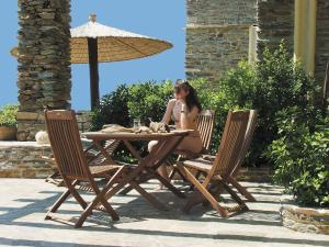 a woman sitting at a wooden table with two chairs at Anastasia Luxury Villas in Gavrio
