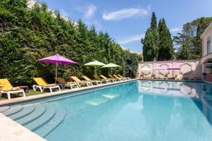 een zwembad met stoelen en parasols naast een gebouw bij Hôtel Mireille in Arles