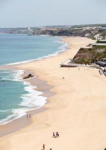 a beach with people walking on the sand and the ocean at Casas da Avó II in Santa Cruz