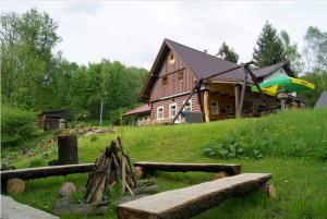 ein großes Holzhaus auf einem grasbewachsenen Hügel mit einer Bank in der Unterkunft MausHaus in Rudník