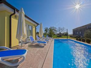 a row of chairs and umbrellas next to a swimming pool at Villa Ketrin in Tinjan