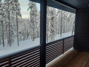 uma janela com vista para árvores cobertas de neve a partir de uma casa em Louhi A em Äkäslompolo