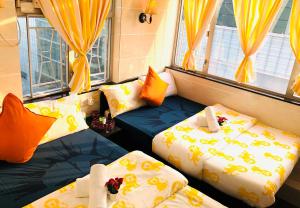 two beds in a room with yellow curtains at David Lounge in Hong Kong