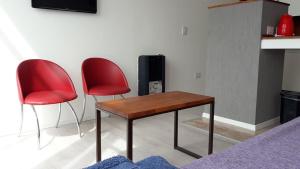 two red chairs and a wooden table in a living room at DEPARTAMENTOS SAAVEDRA dto 3 y 4 in Viedma