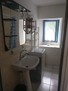 a white bathroom with a sink and a window at la petite peysie in Lisle