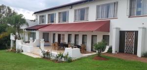 a white house with a red awning at Jacaranda Self Catering Chalets in Krugersdorp