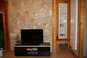 a living room with a tv and a stone wall at Ferienwohnung Am Heidelberg in Blankenburg
