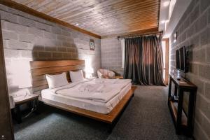 a bedroom with a large bed and a television at Alpine Lounge Kazbegi in Stepantsminda