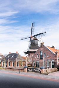 um moinho de vento em cima de um edifício de tijolos em Molen Hunsingo em Onderdendam