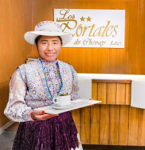 a woman holding a tray with a coffee cup on it at Los Portales de Chivay in Chivay
