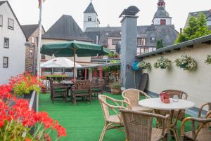 a patio with green grass and tables and chairs at Alte Weinstube Burg Eltz in Treis-Karden