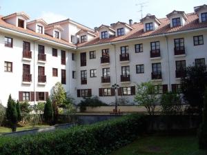 un gran edificio blanco con techo rojo en Apartamentos Club Condal, en Comillas