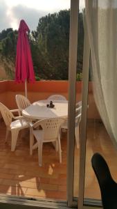 a white table and chairs and an umbrella on a balcony at Les Boramars 4 23 climatisé wifi 300m plage in Argelès-sur-Mer