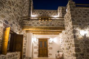 a stone building with a wooden door and lights at To Spiti mas in Sougia