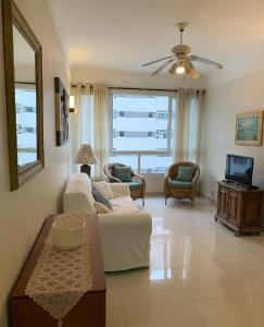 a living room with a white couch and a tv at Lindo apartamento vista mar Pitangueiras Guaruja! in Guarujá