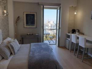 a bedroom with a bed and a kitchen with a balcony at Le Dimore di Don Corrado in Trani