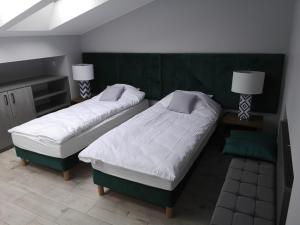 two beds in a room with two tables and two lamps at Apartamenty Rynek in Września