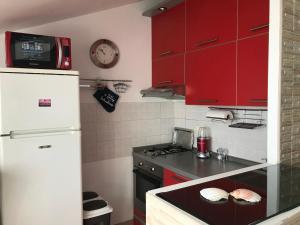 a kitchen with red cabinets and a white refrigerator at Uphill Opatija Apartment in Opatija +30 photos