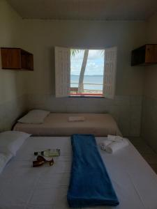 マンゲ・セッコにあるPousada Grão de Areia Beira Marのベッドルーム1室(ベッド2台付)、海の景色を望む窓が備わります。